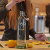 Photo of a woman squeezing orange juice into a glass bottle made in Europe